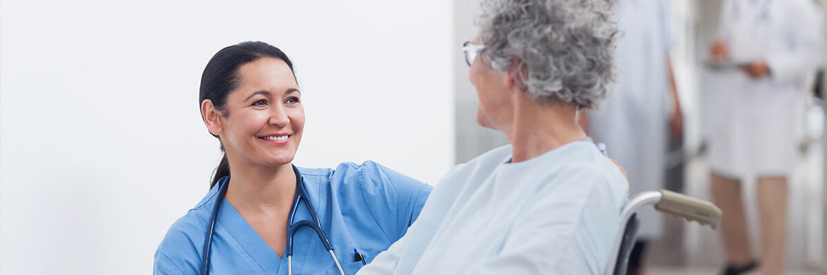 Nurse smiling at patient in wheelchair.